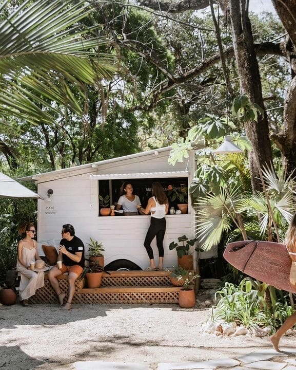 A group of people enjoying food and conversation around a food truck in an outdoor space.